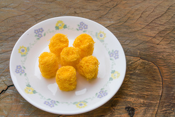 Sweet egg floss in a dish with fabric on wood background kind of Thailand traditional dessert in thai name of Foi Thong
