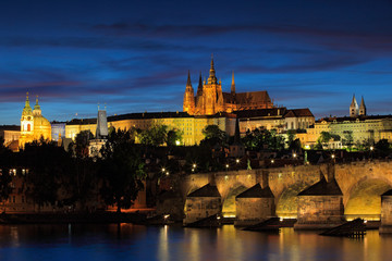 Fototapeta na wymiar The Prague Castle, gothic style, largest ancient castle in the world, and Charles Bridge are the symbols of Czech capital, built in medieval times. Twilight view of Prague, after sunset