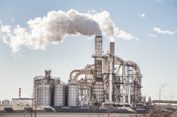 Chimneys and silos of a factory. - Powered by Adobe