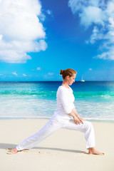 Fototapeta na wymiar Young woman practices yoga on the beach