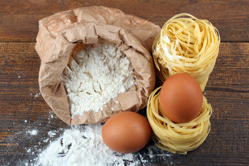pasta with eggs and flour scattered on a brown wooden table