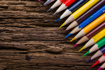 Row of colored drawing pencils closeup on old grunge natural woo