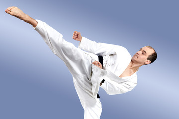 Man in karategi beats high kick leg