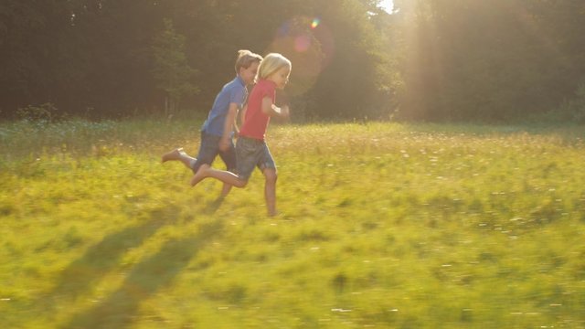 Two happy kids running competition over field in sunshine