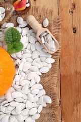 Pumpkin with pumpkin seeds on wood background.