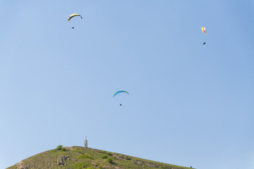 Fototapeta na wymiar Multiple paragliders with their parachutes on a sunny day near city of Koktebel in the Crimea, Ukraine