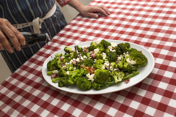 Fresh broccoli salad with bacon and feta cheese, pouring over some good quality balsamic vinegar.

