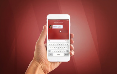 I love you message on smart phone display. Phohe in woman hand with red background.