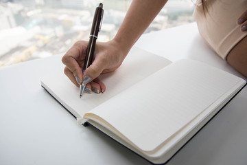 Woman hand is writing to notebook