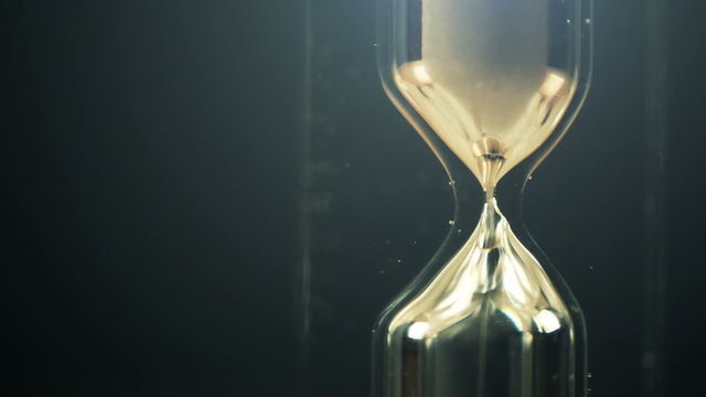Hourglass macro shot in dark interior, passing of time concept.