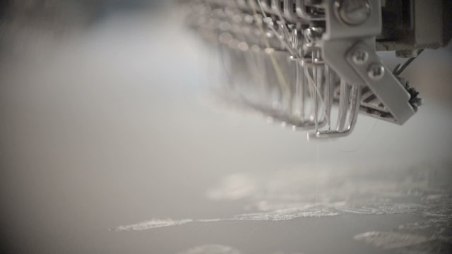 Automatic sewing machine embroider the butterfly white pattern on white fabric. Industrial textiles. Macro Slow motion
