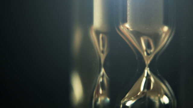 Hourglass macro shot in dark interior, passing of time concept.