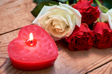 Fototapeta premium bunch of red roses with red candle on wooden background
