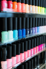 Set of different nail varnishes on shelves in cosmetic store