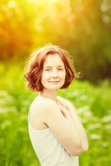 Outdoor portrait of beautiful young woman who hugging herself at summer sunset. Orange and yellow natural toning, golden sunshine. Femininity and womanhood concept