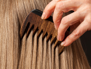 Fototapeta premium Female hand combing beautiful long hair