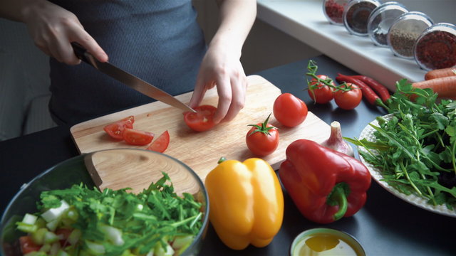Young woman cutting vegetables in the kitchen for fresh salad
