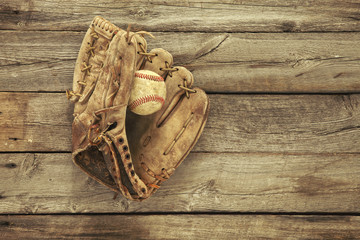 Old baseball and mitt on rough wood background