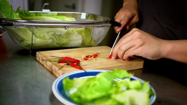 Man Slices Chili Lettuce on Cutting Board with White Knife 60 fps