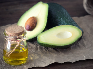 bottle of avocado essential oil with fresh avocado fruit closeup