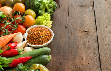 Uncooked brown millet in a bowl with vegetables
