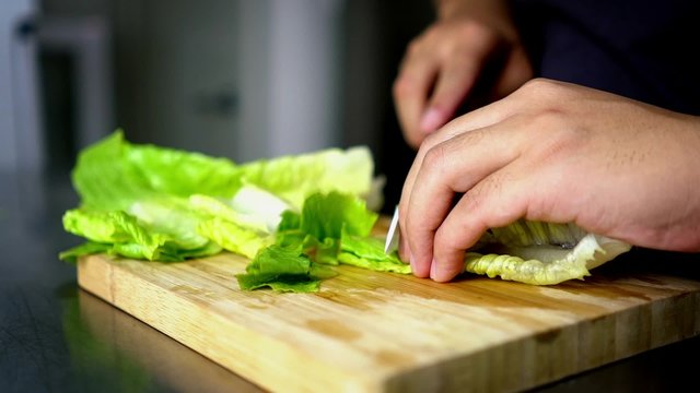 Man Cutting Lettuce on Board Cutting with  Ceramic White Knife - Close Up 60 fps