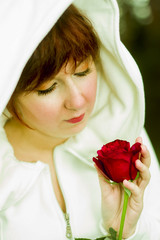 A beautiful woman in a white hood, holding a red rose