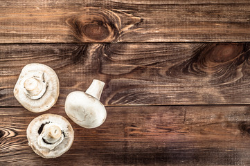 Mushrooms champignons on rustic wooden background.