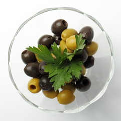 Olives. / Olives with parsley in a glass container.