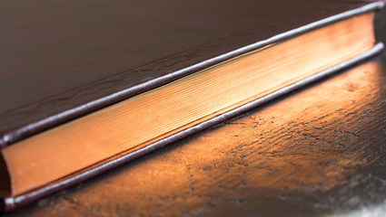 a closed book with gold color edge. shallow depth of field