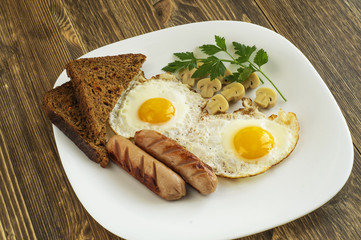 Breakfast with fried eggs, sausage, marinade mushrooms and bread