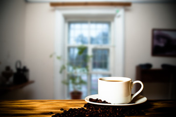 Coffee in a cup on wooden table opposite a defocused the interio