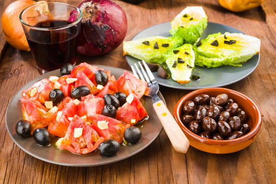 several plates of salad, tomato, olives and lettuce