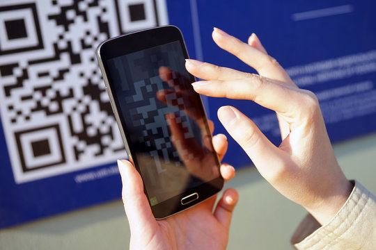 MOSCOW, RUSSIA - DECEMBER 16, 2015: The girl scans QR code with mobile smart phone.