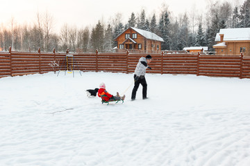 Dad daughter and dog sledding in backyard