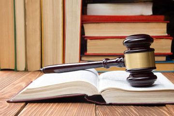 Law book with wooden judges gavel on table in a courtroom or law enforcement office.