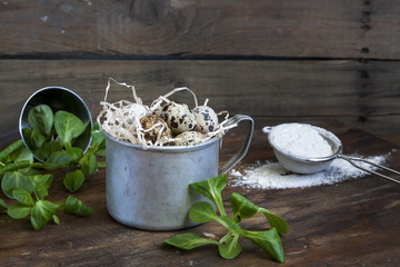 Quail easter eggs in a aluminum cup, green lettuce and flour on wooden table