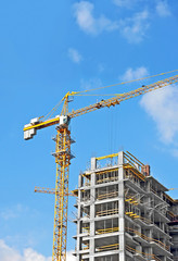 Crane and building construction site against blue sky