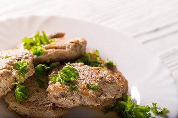 Some pieces of fried meat with parsley greens on a white plate