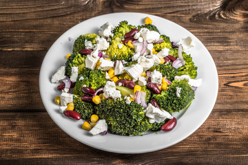 Vegetarian salad with broccoli, beans, corn, onion and feta cheese.