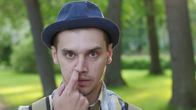 Portrait of boy in hat pick nose and then eat nose thing  . Outdoor. Summer