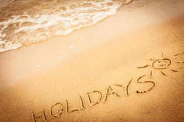 The word holidays written in the sand on a beach