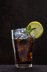 glass of cola or coke with ice cubes, lemon slice and peppermint