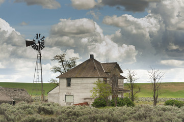 Abandoned Farmhouse. A boarded up and long abandoned farmhouse and windmill seen in the palouse...