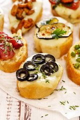 Crostini with addition of melted mozzarella cheese,  black olives and fresh thyme
