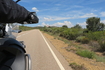 Driver riding motorcycle on an asphalt road through forest
