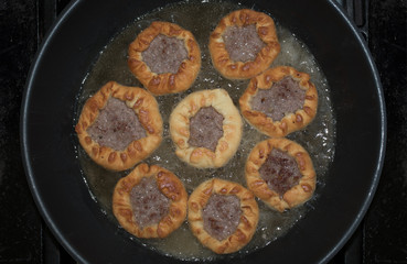 Deep fried pastries belyashi with a beef filling fried in a pan