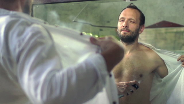 Young man spraying deodorant on his body in the bathroom, shot at 240fps
