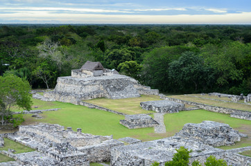 Aerial view to Mayan ruins and house on top of pyramid surrounded by jungle 