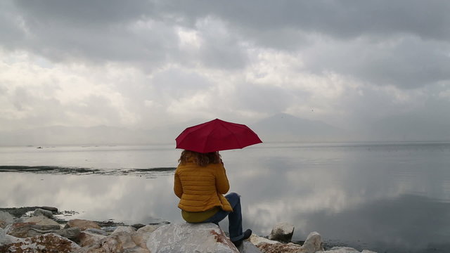 Portrait of a woman with umbrella  sitting at the sea side